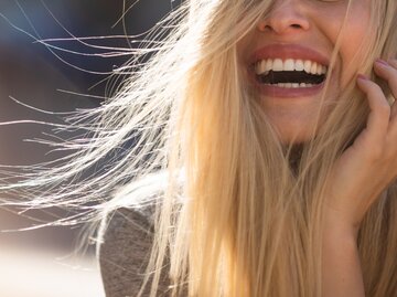 Frau mit blonden langen Haaren lacht, abgeschnittenes Foto untere Gesichtshälfte | © GettyImages/Martin Novak