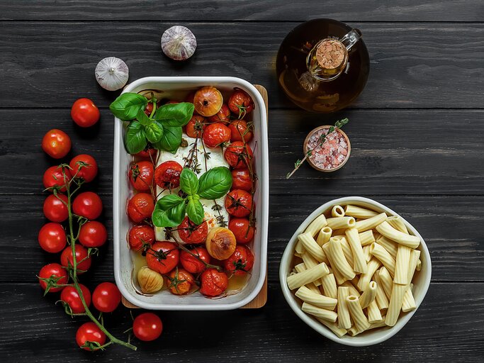 Feta und Tomaten in einer Ofenform, daneben eine Schale mit Nudeln | © gettyimages.de | Jane Vershinin