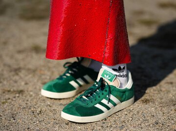 Eine Frau trägt grüne Adidas Gazelle mit einem roten Paillettenrock.  | © Getty Images/Edward Berthelot