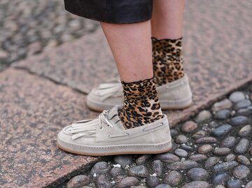 Frau trägt beige Bootsschuhe mit Leoparden-Socken auf der Straße. | © Getty Images/Edward Berthelot