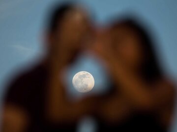 Ein Paar macht ein „Selfie“-Foto vor einem Vollmond. | © Getty Images/Bloomberg Creative Photos