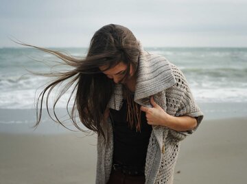 Frau steht am Strand und blickt auf ihre Beine | © Adobe Stock/LP Design