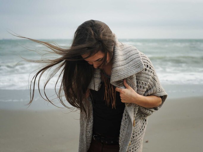 Frau steht am Strand und blickt auf ihre Beine | © Adobe Stock/LP Design