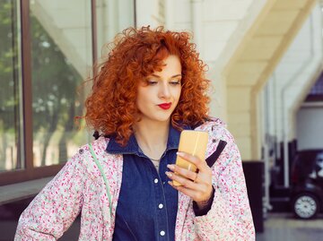 Eine Frau sieht den TikTok-Trend auf ihrem Handy und schaut besorgt | © GettyImages/HbrH