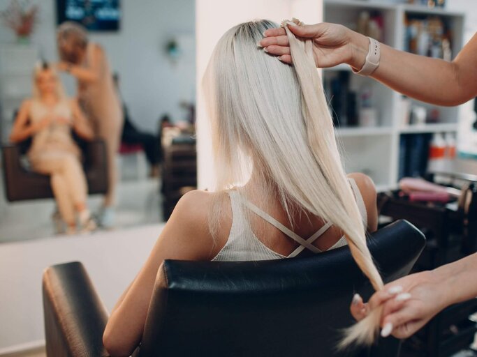 Person beim Friseur bekommt Extensions | © Getty Images/primipil