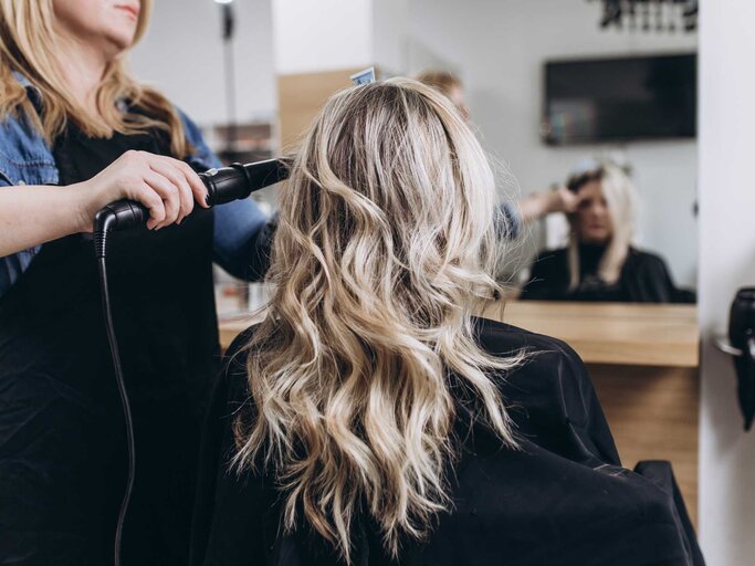 Frau werden Haare beim Friseur gelockt | © Getty Images/Group4 Studio