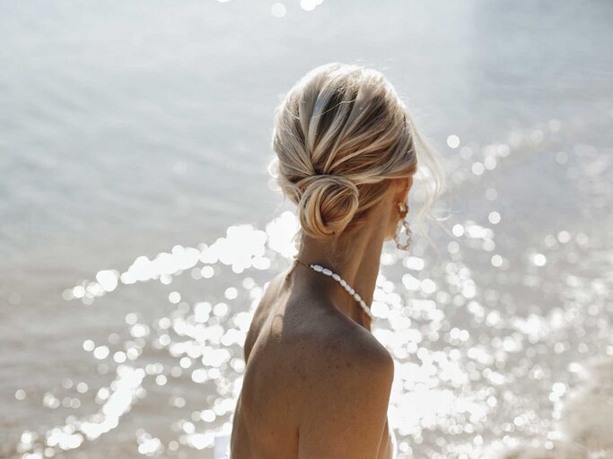 Frau mit zurückgebundenen Haaren am Strand. | © Adobe Stock/andriychuk