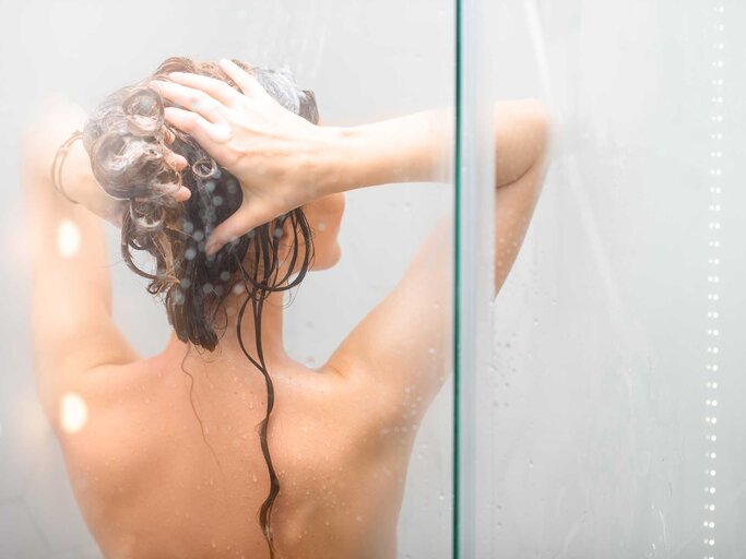 Junge brünette Frau steht unter der Dusche und wäscht sich die Haare | © Adobe Stock/rh2010