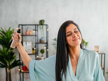 Frau sprüht Haarspray vor dem Styling auf die Haare. | © Getty Images/urbazon