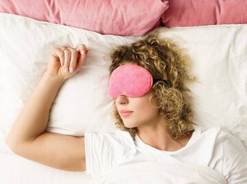 Person mit Locken und Schlafmaske in Bett | © Getty Images/Jun