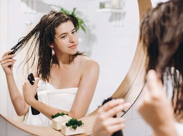 Frau steht vor dem Spiegel und kämmt sich die Haare | © Getty Images/Bogdan Kurylo