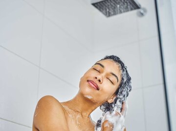 Frau schäumt in der Dusche ihre Haare ein. | © Getty Images/Moyo Studio