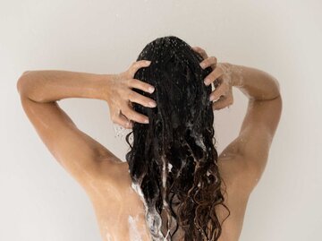 Frau wäscht sich unter der Dusche die langen Haare | © Adobe Stock/fizkes