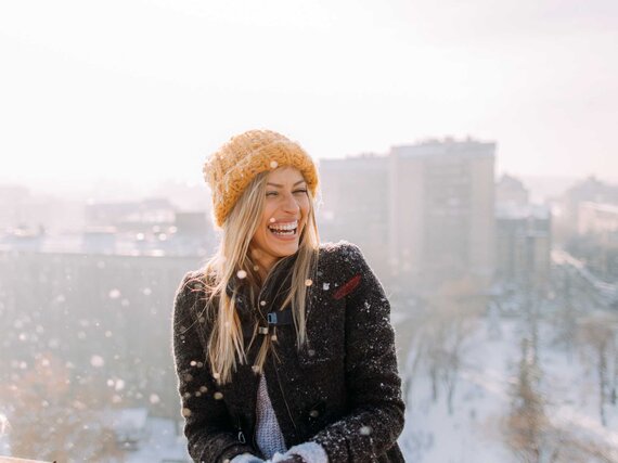 Frau lacht mit Mütze im Winter.