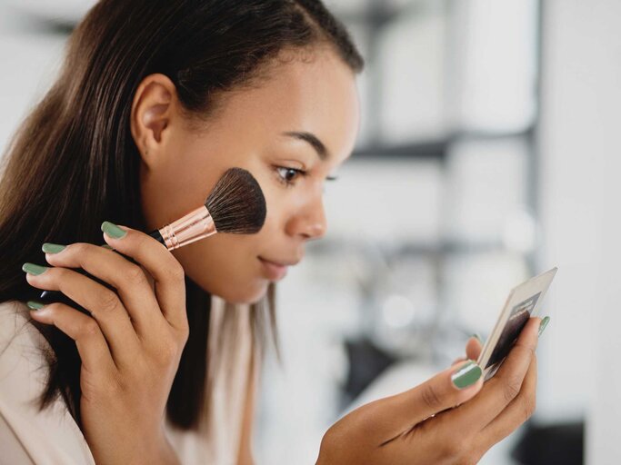 Junge Frau trägt Make-up auf ihr Gesicht auf | © Getty Images/Ablozhka