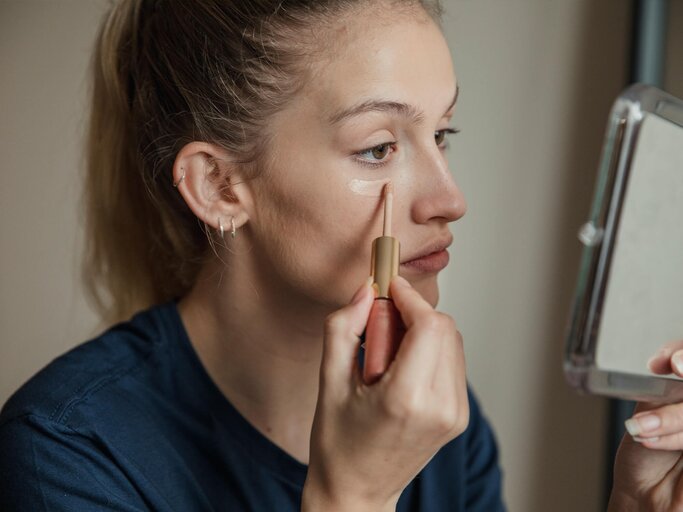 Frau trägt Concealer auf, um Augenringe zu entfernen | © Getty Images