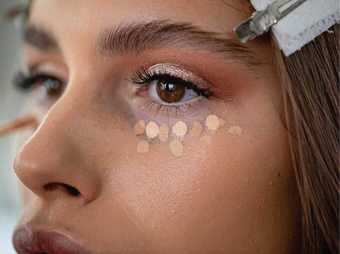 Concealer-Tupfen auf dem Augenlid einer Frau. | © Getty Images/FluxFactory