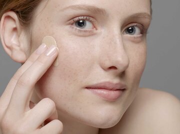 Frau trägt Make-up auf dem Gesicht auf | © Getty Images/Emma Kim