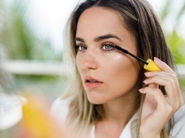 Reflexion in einem Spiegel einer Frau, die Mascara auf ihre Augen aufträgt | © Getty Images/skynesher