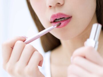 Frau trägt sich mit einem Pinsel Lippenstift auf | © Adobe Stock/TAGSTOCK2