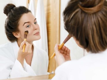 Junge Frau trägt Make-up vor dem Spiegel auf | © Adobe Stock/blackday