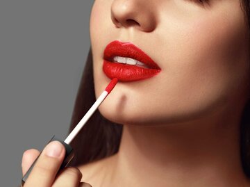 Frau trägt sich roten Lippenstift auf | © Adobe Stock/Pixel-Shot