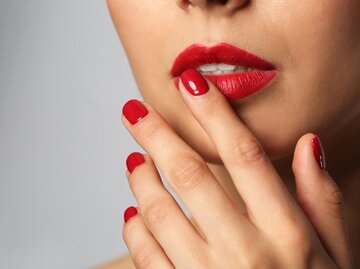 Frau fasst sich mit Fingern an rote Lippen | © AdobeStock/Pixel-Shot