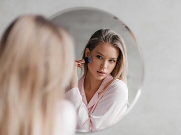 Frau schminkt sich vor dem Spiegel | © Adobe Stock/Prostock-studio