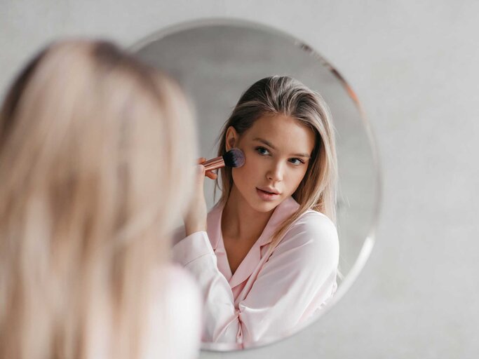 Frau schminkt sich vor dem Spiegel | © Adobe Stock/Prostock-studio