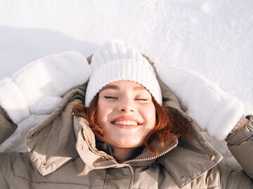 Person lachend in Sonne im Winter | © Getty Images/Galina Zhigalova