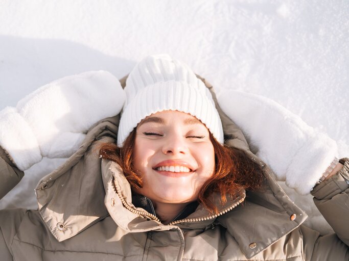 Person lachend in Sonne im Winter | © Getty Images/Galina Zhigalova