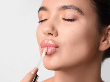 Frau trägt sich Lipgloss auf die Lippen auf | © Adobe Stock/Pixel-Shot