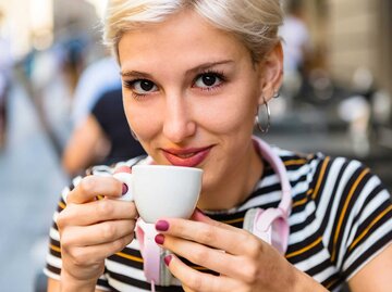 Eine blonde Frau trinkt einen Espresso im Café. | © Adobe Stock/tunedin