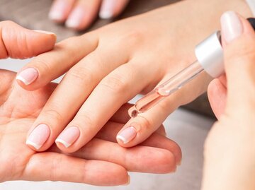 Manikürte Finger werden mit Nagelöl gepflegt | © Adobe Stock/okskukuruza