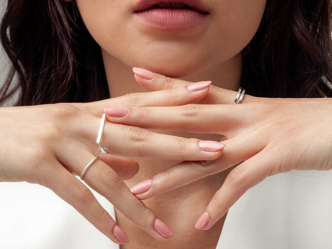 Frau mit rosa lackierten Nägeln und Ringen an den Fingern | © Adobe Stock/duyviet