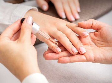 Manikürte Finger werden mit Nagelöl versorgt | © Adobe Stock/okskukuruza