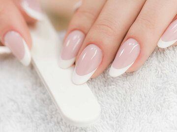 Gelnägel mit French Design halten eine Nagelfeile | © Adobe Stock/Milan