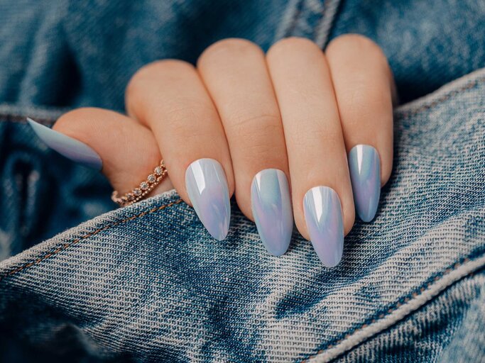 Frau trägt Jeansjacke und hat blaue Chrome Nails an ihrer Hand | © Adobe Stock/Dmitri