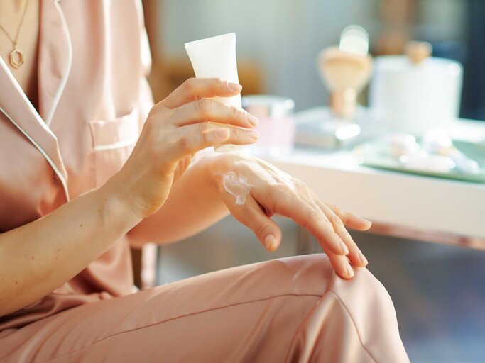 Frau cremt sich ihre Hände mit Handcreme ein | © Adobe Stock/Alliance