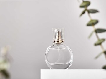 Transparenter Parfum-Flakon vor einem grauen Hintergrund | © Adobe Stock/colnihko