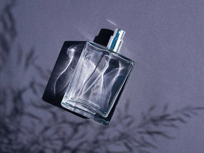 Parfum-Flakon vor einem blauen Hintergrund | © Adobe Stock/Alex Shi