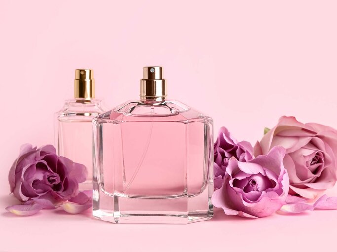 Parfum-Flakons und Blumen vor einem rosa Hintergrund | © Adobe Stock/New Africa