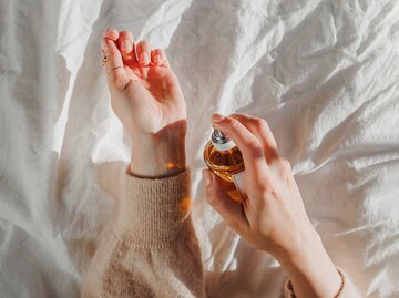 Frau sprüht sich Parfum auf die Handgelenke | © Getty Images/Chiociolla