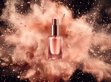 Parfum-Flakon vor rosa Puder-Explosion | © AdobeStock/bani/Mit KI generiert