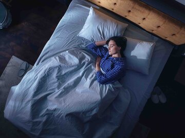 Frau liegt im Bett vom Fenster kommt leichtes Licht ins Zimmer | © Getty Images/gorodenkoff