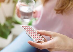 Person mit Pillenblister und Wasserglas