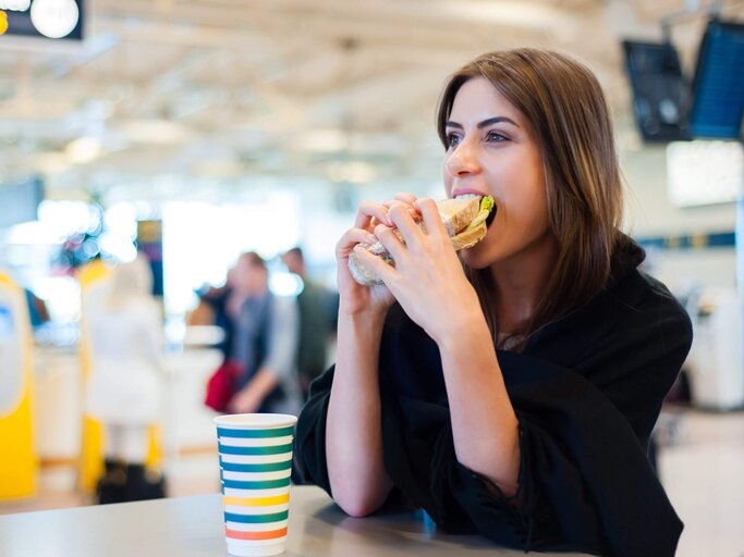 Person isst Sandwich an Flughafen | © Getty Images/VladTeodor