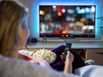 Person beim Netflix schauen mit Popcorn | © Getty Images/grinvalds