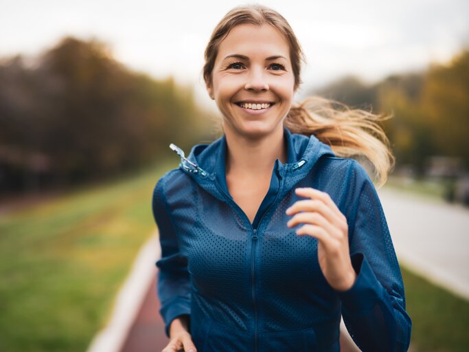 Junge, lachende Frau beim Joggen in der Natur | © AdobeStock/djoronimo