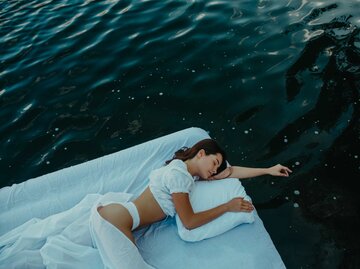 Frau liegt auf Luftmatratze im Wasser mit Bettzeug | © Adobe Stock/Stanislav